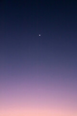 Beautiful night sky with a crescent moon. The sky is dark blue at the top and light blue at the bottom.
