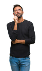 Adult hispanic man wearing glasses over isolated background with hand on chin thinking about...
