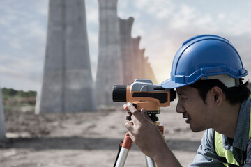 Fototapeta premium surveyor at work. construction worker using level camera. Surveyor with looking throughout digital level. Surveyors work with digital level onsite construction.
