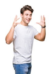 Young handsome man wearing white t-shirt over isolated background celebrating mad and crazy for success with arms raised and closed eyes screaming excited. Winner concept