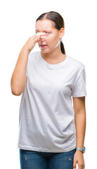 Young beautiful caucasian woman over isolated background smelling something stinky and disgusting, intolerable smell, holding breath with fingers on nose. Bad smells concept.