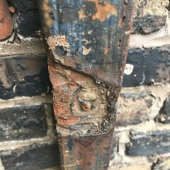   Close-up of a weathered brick wall with flaking paint and a visible hole