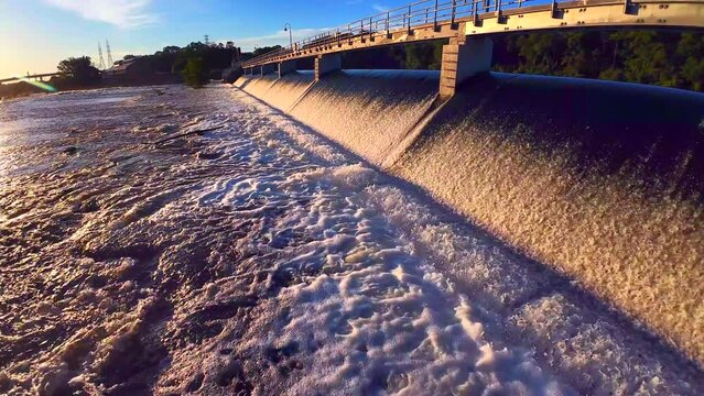 Dawn drone flight over rapids below the waterfall by the dam
