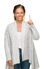 Beautiful middle age adult woman wearing winter sweater over isolated background showing and pointing up with finger number one while smiling confident and happy.