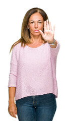 Beautiful middle age adult woman wearing winter sweater over isolated background doing stop sing with palm of the hand. Warning expression with negative and serious gesture on the face.