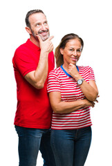 Middle age hispanic couple in love over isolated background looking confident at the camera with smile with crossed arms and hand raised on chin. Thinking positive.