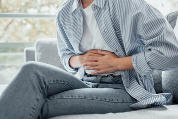 Sick young woman in pain holding belly stomach feeling hurt abdomen ache gastritis pancreatitis...