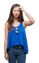 Young asian woman over isolated background angry and mad raising fist frustrated and furious while shouting with anger. Rage and aggressive concept.