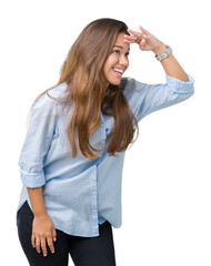 Fototapeta premium Young beautiful brunette business woman over isolated background very happy and smiling looking far away with hand over head. Searching concept.