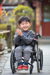 A young boy in a wheelchair claps his hands with excitement, perfect for use in education or disability awareness campaigns