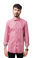 Young handsome man wearing pink shirt over isolated background In shock face, looking skeptical and...