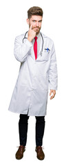 Fototapeta premium Young handsome doctor man wearing medical coat Pointing to the eye watching you gesture, suspicious expression