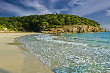 Obraz premium Serene Cala Escorxada Beach with Lush Greenery, Menorca