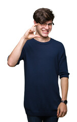 Young handsome man wearing glasses over isolated background smiling and confident gesturing with hand doing size sign with fingers while looking and the camera. Measure concept.