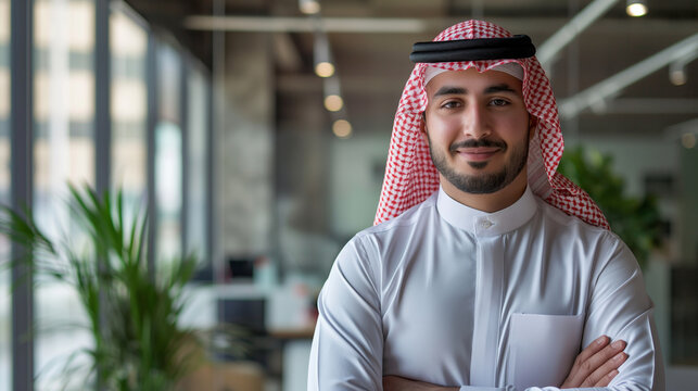 Dressed in traditional Arab attire, a standing and dynamic Arab handsome guy in a modern office with minimalist decor, front light, smiling confidently and looking directly into th