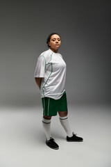 A woman in a white jersey and green shorts stands ready for the game.