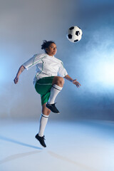 Naklejka premium A female soccer player jumps high, eyes fixed on the ball, about to make a powerful play.