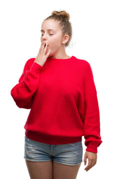 Young blonde woman wearing bun and red sweater bored yawning tired covering mouth with hand. Restless and sleepiness.