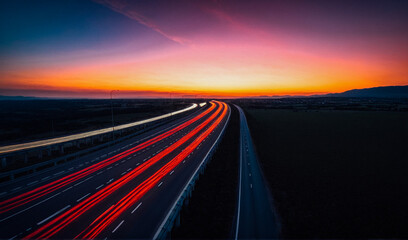 Fototapeta premium Blurred rays of light from cars passing along the highway at dawn. View from above. Scenery.