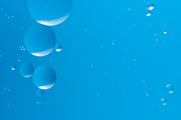 Blue bubbles float in a gradient of light blue, forming soothing and minimalistic abstract pattern serene background.