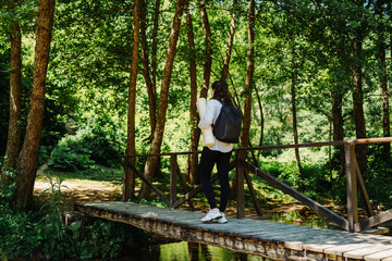 One young caucasian woman is taking a break from hiking near the river and waterfall in the forest	