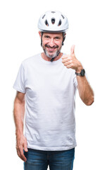 Middle age senior hoary cyclist man wearing bike safety helment isolated background doing happy thumbs up gesture with hand. Approving expression looking at the camera with showing success.
