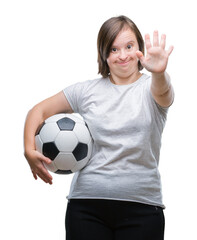 Young adult woman with down syndrome holding soccer football ball over isolated background with...