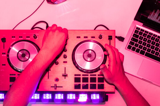 DJ adjusting equipment with intense pink lighting