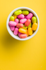 Colorful hard mint Candies in bowl on yellow background. Top view.