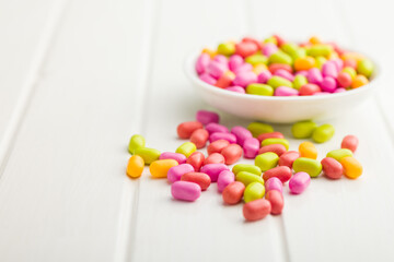 Colorful hard mint Candies in bowl on white table.