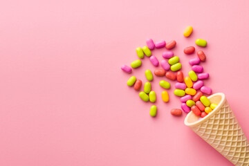 Colorful hard mint Candies in ice cream cone on pink background. Top view.
