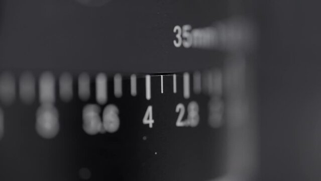 Close-up view of 35mm lens aperture scale in monochrome. Detailed macro shot of a 35mm lens displaying f-stop numbers