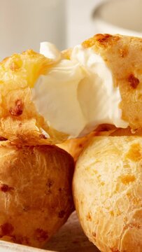 Vertical video of cheese bread with cream cheese and a cup of black coffee and butter, on a checkered picnic tablecloth	