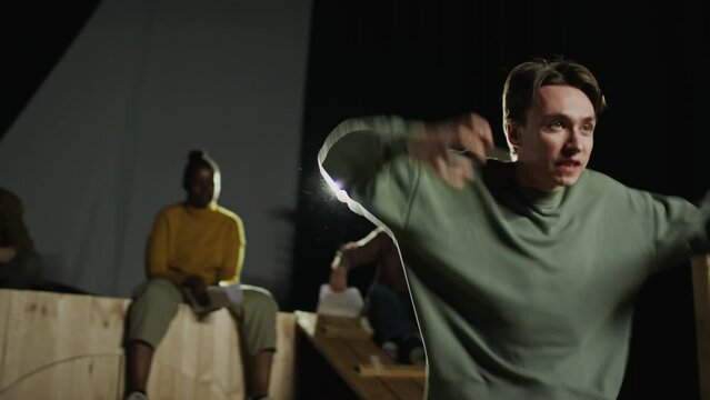 Young emotional actor giving dramatic performance on stage in thetre during rehearsal