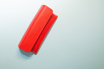 Red coloured leather glasses case. Copy area, blue background.