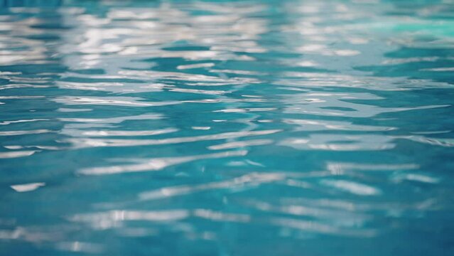 Scene of a tranquil swimming pool surface with water waves and defocused reflections in vibrant colors. Ideal concept for relaxation and aquatic designs, slow motion
