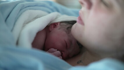 Newborn baby resting on mother's chest right after birth emphasizing skin to skin contact, real...