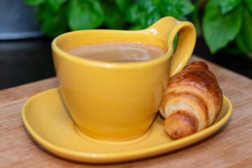 breakfast with croissant and coffee,Yellow cup with coffee and croissant on a plate set on a wooden board, breakfast time, French breakfast, coffee break,croissant and coffee, 