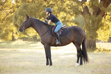 Young equestrian girl woman with horse equine in english tack and riding attire hunter jumper