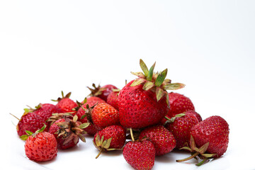 Heap of fresh ripe natural strawberries on a white saucer. Freshly picked garden strawberries. Detailed photo of strawberries on an abstract background. Close up view