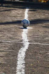 Pelota de futbol en cancha de tierra .