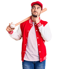Young handsome man holding baseball bat and ball serious face thinking about question with hand on...