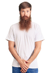 Obraz premium Handsome young red head man with long beard wearing casual white tshirt skeptic and nervous, frowning upset because of problem. negative person.