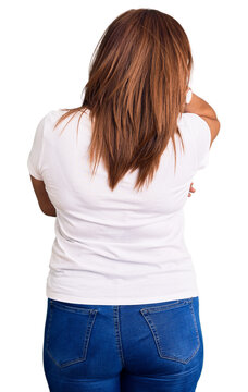 Middle age latin woman wearing casual white tshirt backwards thinking about doubt with hand on head