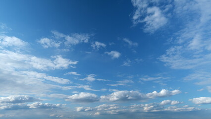 Fototapeta premium Dramatic moving white cumulus and cirrocumulus clouds or puffy fluffy cloudscape on beautiful sunny blue sky. Timelapse.