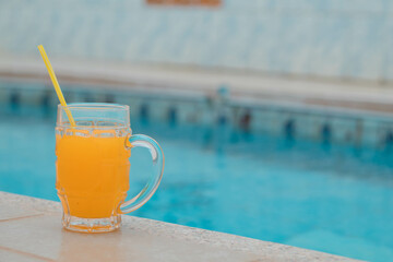 un vaso de zumo de naranja, jugo delicioso ,sol, costado piscina, día caluroso, bebida refrescante, disfrute, bebida