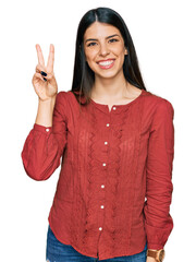 Young hispanic woman wearing casual clothes showing and pointing up with fingers number two while smiling confident and happy.