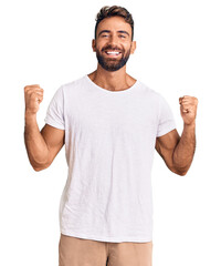 Young hispanic man wearing casual white tshirt celebrating surprised and amazed for success with...