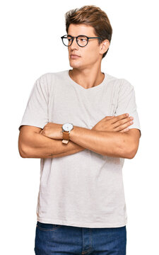 Handsome caucasian man wearing casual clothes and glasses looking to the side with arms crossed convinced and confident