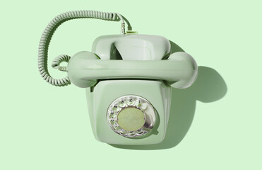 Old green phone with dial plate  on green pastel background